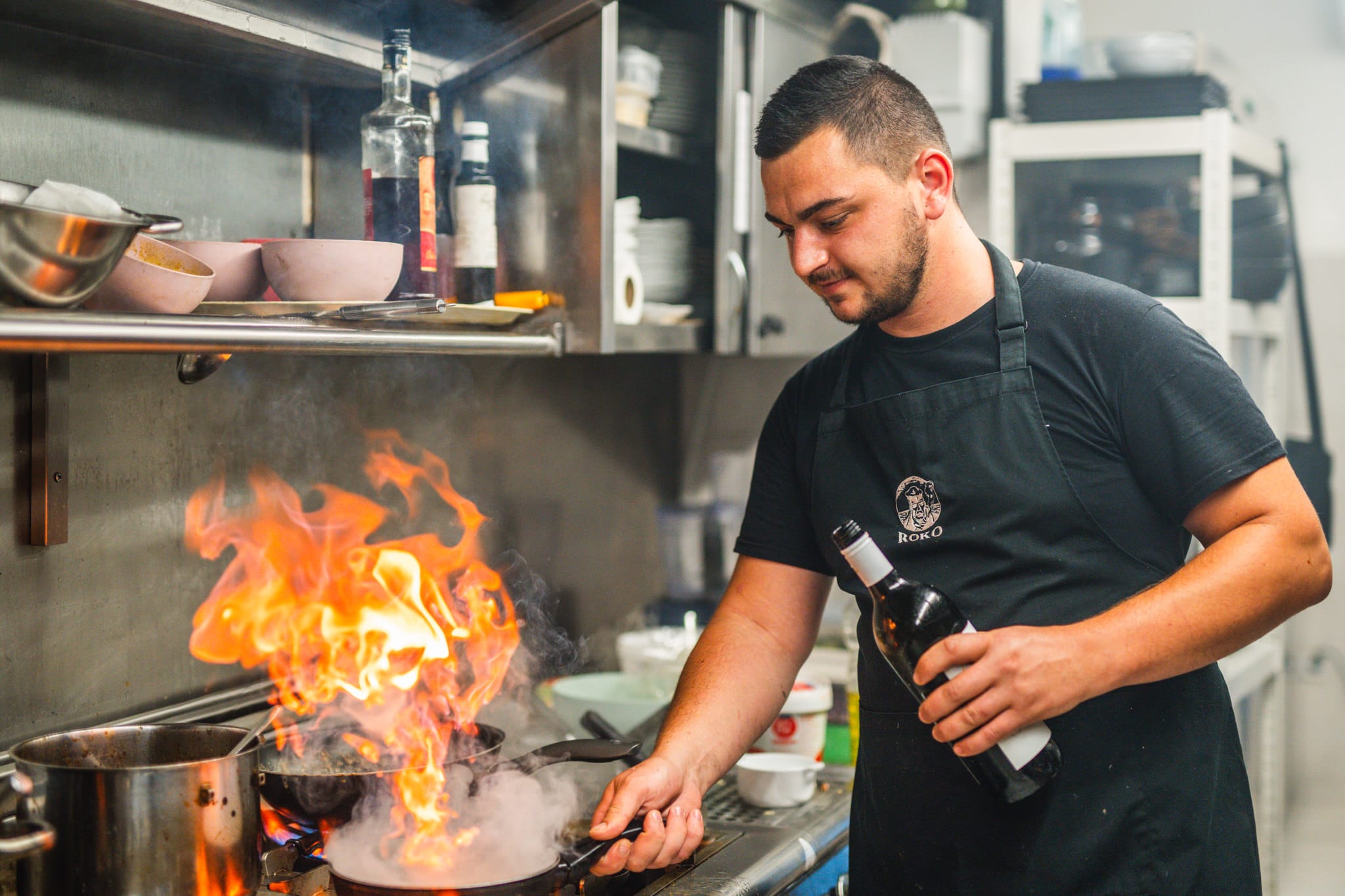 Chef finishing a dish with wine over flames