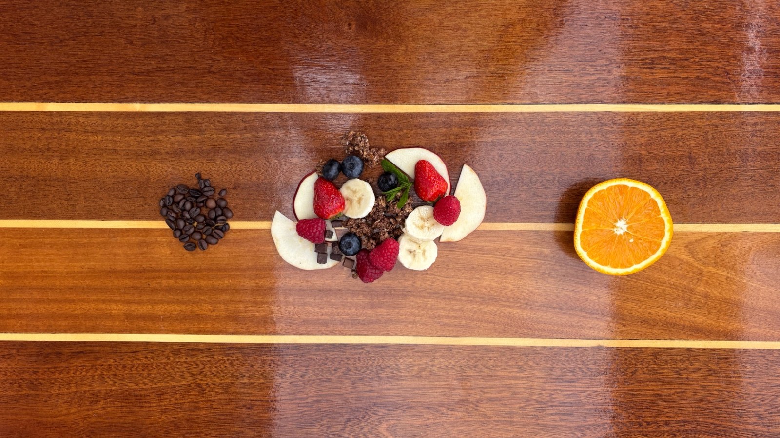 Fresh breakfast ingredients: orange, granola, berries, coffee beans