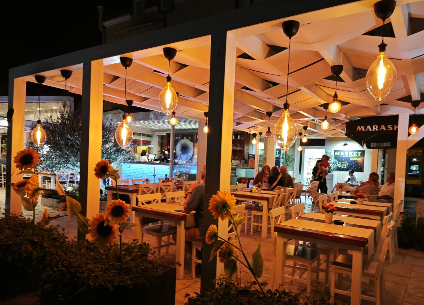 Pergola with sunflowers and warm glass pendant bulbs at night