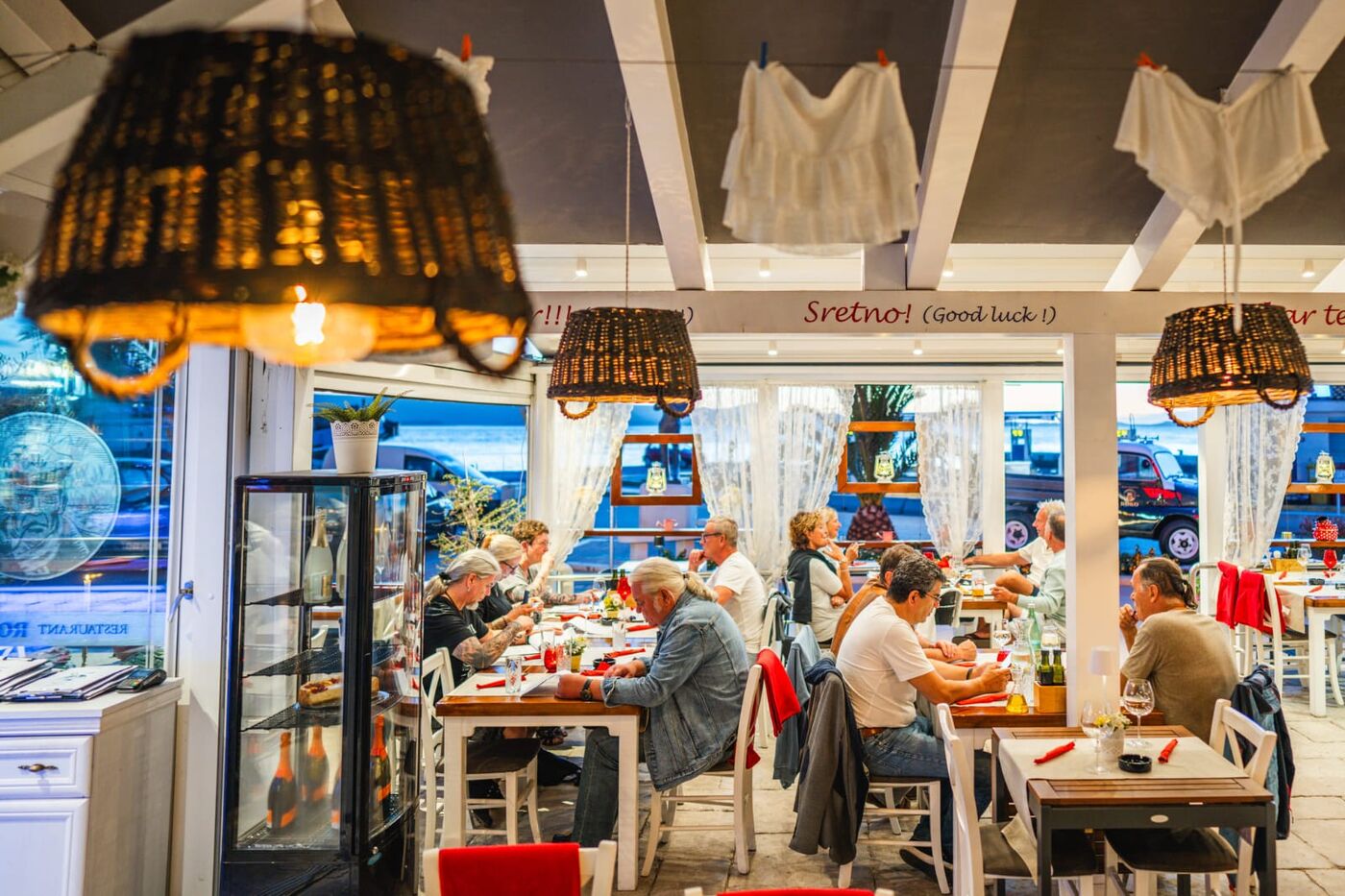 Roko interior with wicker pendant lamps and guests at dinner